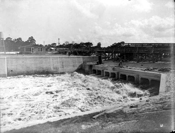 A wide, straight-walled Florida drainage canal cutting through flat scrub land, characteristic of mid-century engineering.